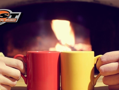Photo of two people touching their drinking mugs together in front of a fireplace